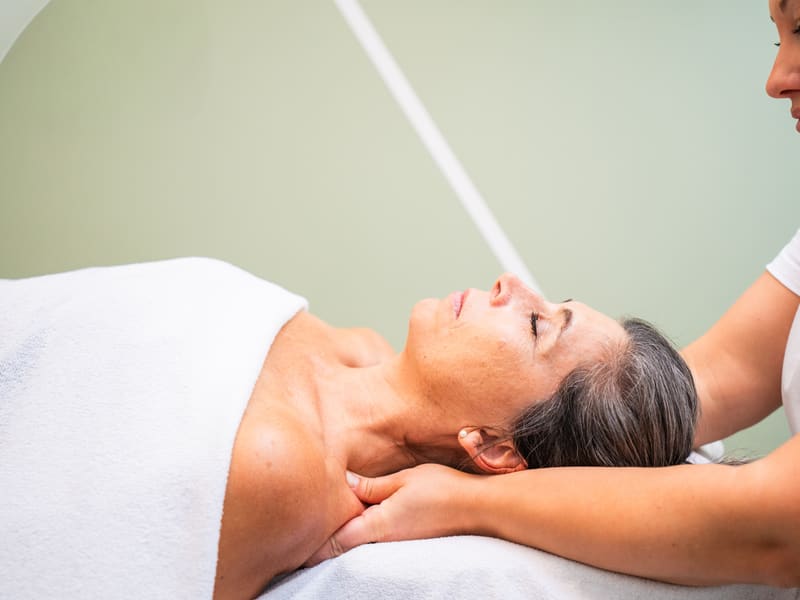 Sanfte Behandlung im Nackenbereich einer liegenden Patientin