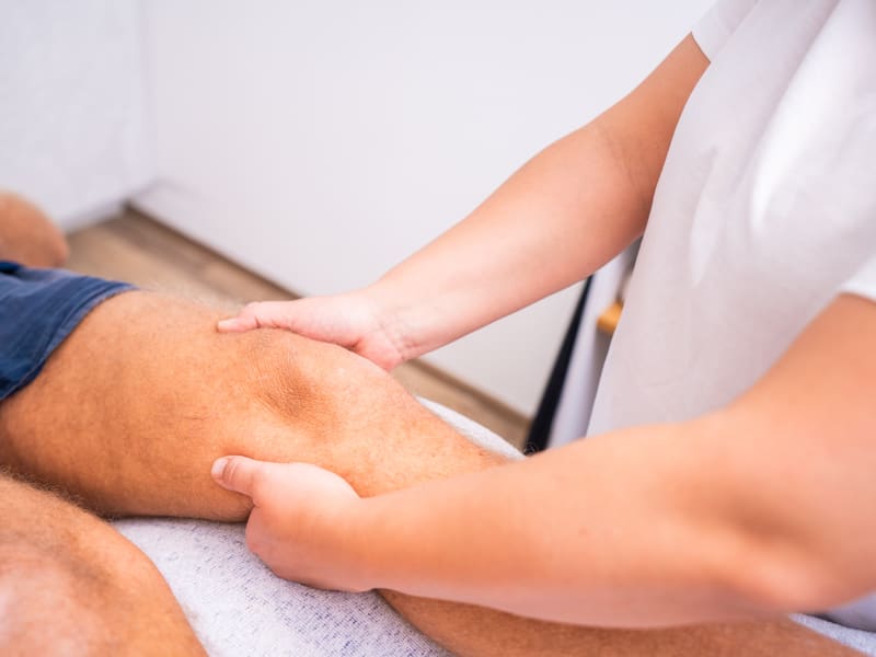 Therapeutin behandelt den Oberschenkel eines Patienten