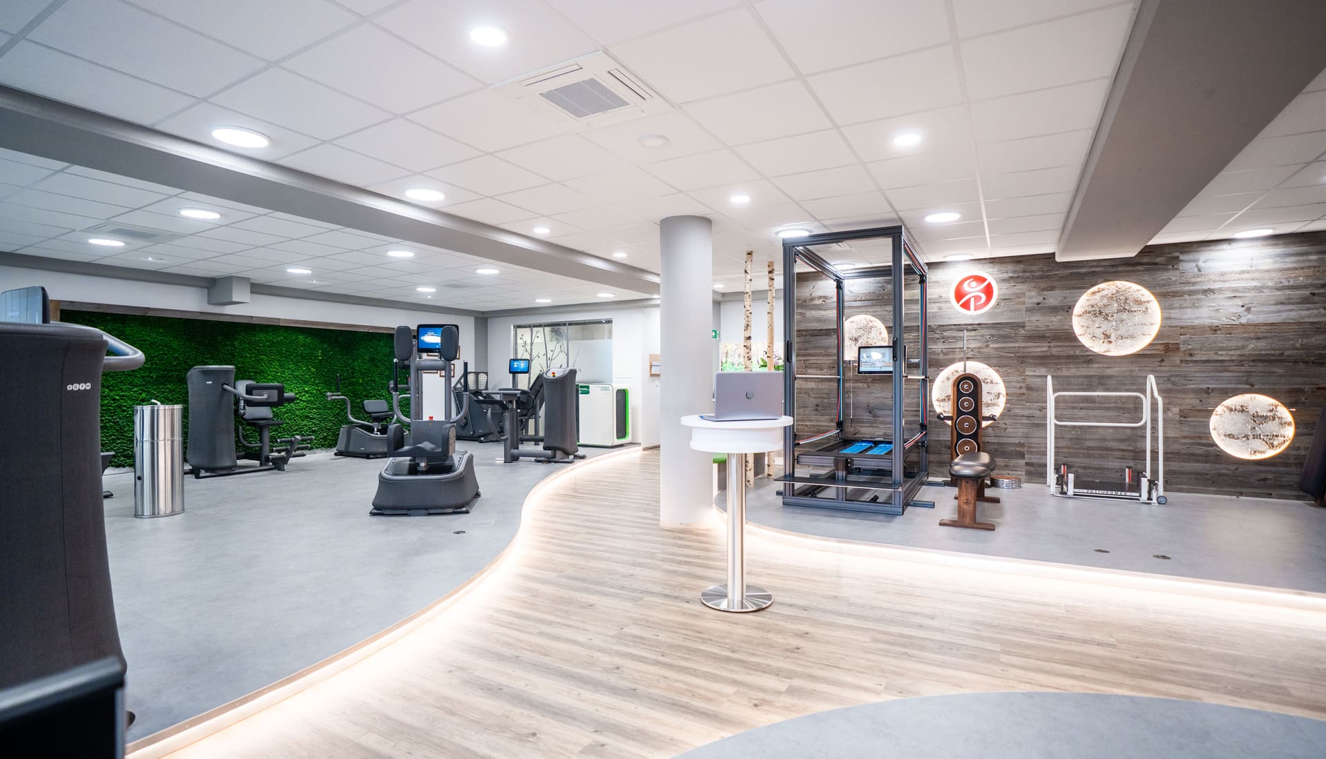 Heller, moderner Trainingsbereich mit Geräten und Moos-Wand