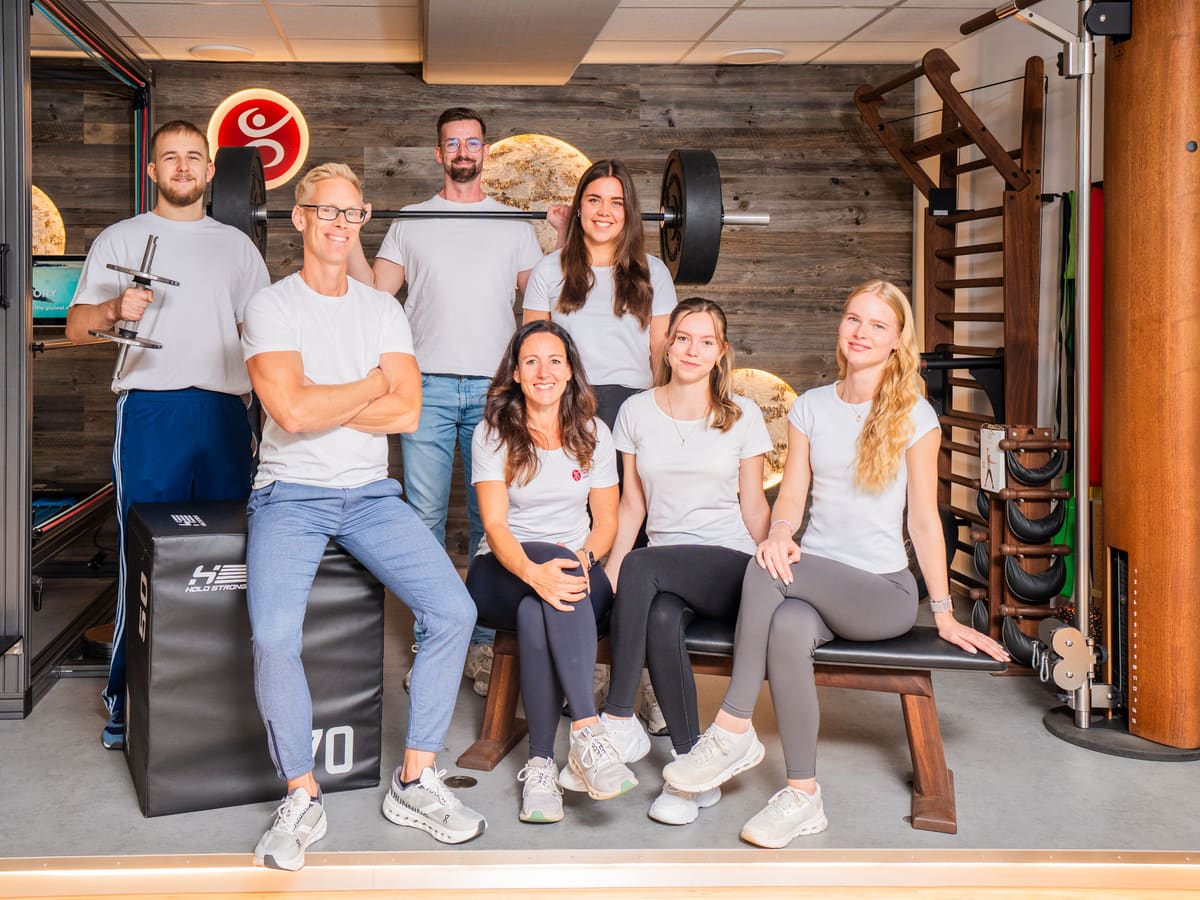 Team im Bereich mit Holzwand und Praxislogo